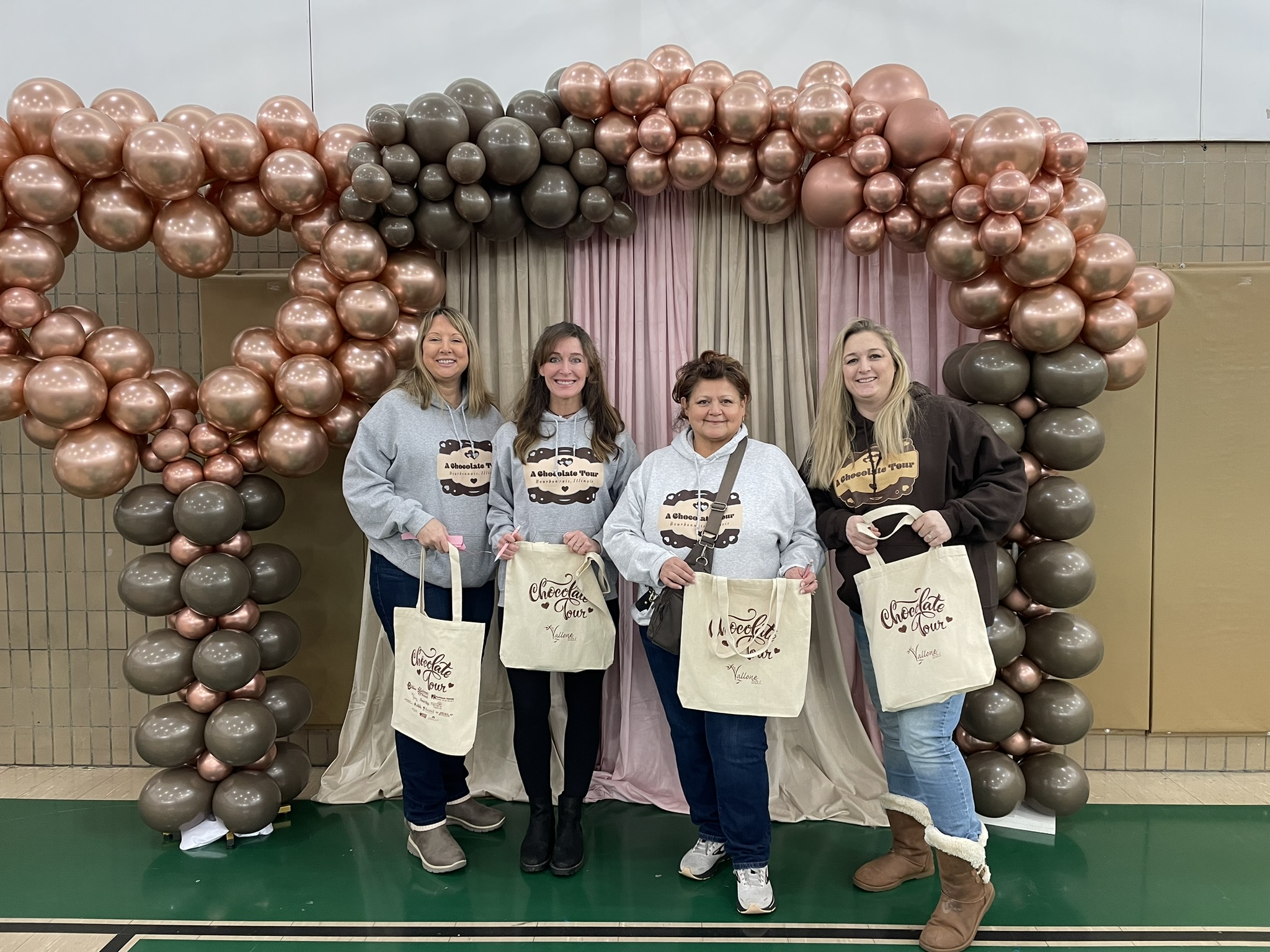 Four women at the chocolate tour under a balloon arch